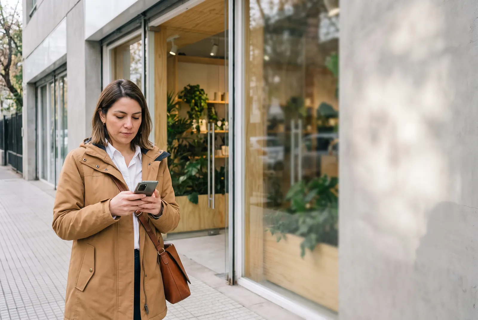 Ejecutiva comercial revisa en el celular la ficha de un cliente antes de entrar a su local