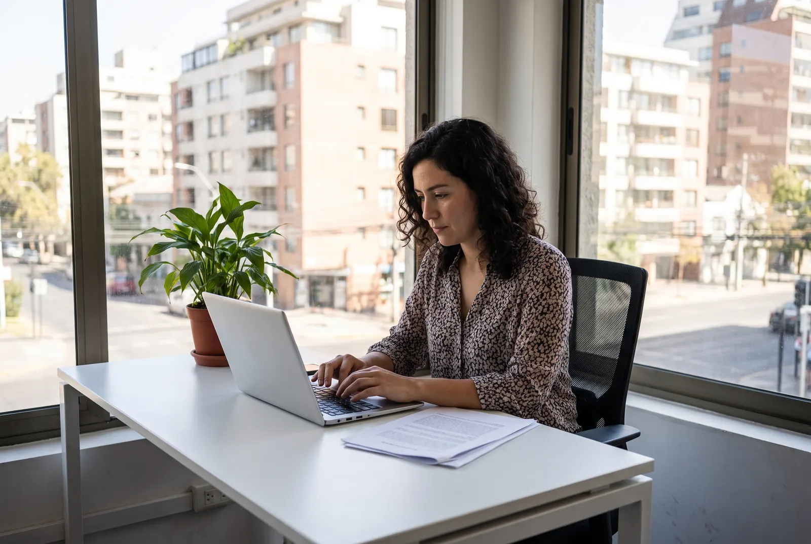 Administrativa de una pyme revisa facturas en su escritorio junto al notebook