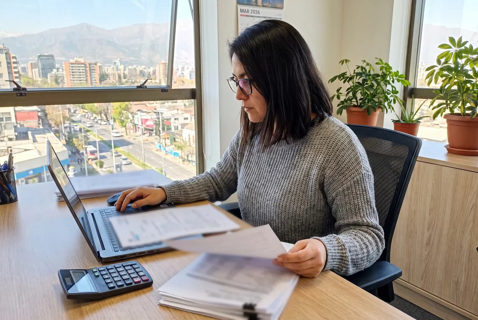 Contadora prepara liquidaciones de sueldo a fin de mes con notebook y calculadora